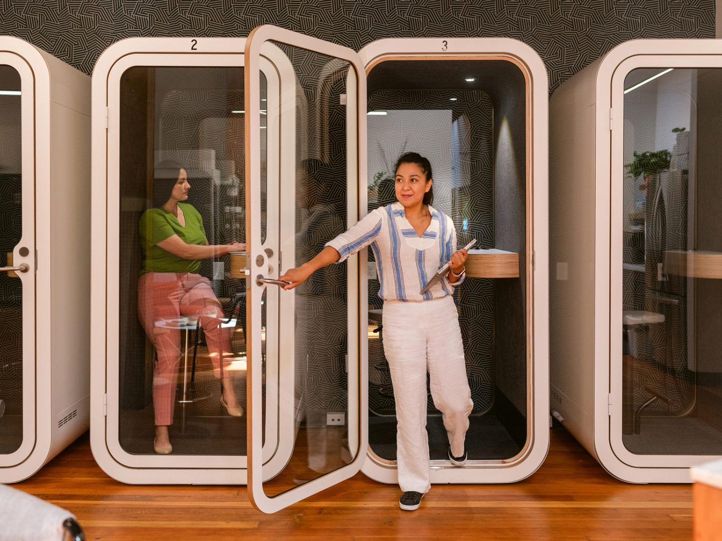 Image of woman stepping out of small meeting booth